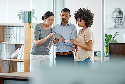 Buy stock photo Shot of office colleagues having a discussion over a digital tablet