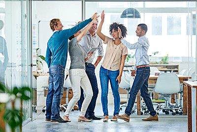 Buy stock photo Shot of a positive group of coworkers high-fiving each other while standing in the office