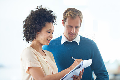 Buy stock photo Shot of two business people discussing ideas on a notepad
