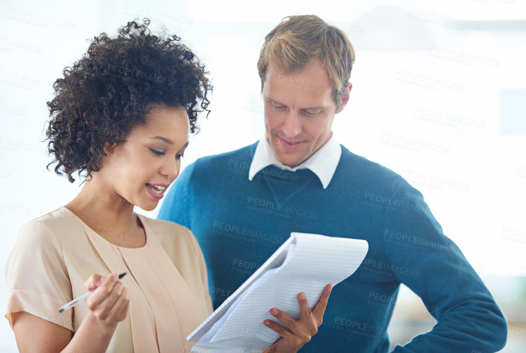 Buy stock photo Shot of two business people discussing ideas on a notepad