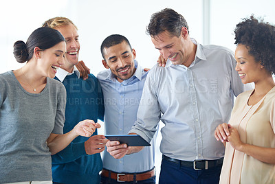 Buy stock photo Shot of a group of colleagues using a digital tablet together