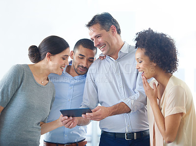 Buy stock photo Shot of a group of colleagues using a digital tablet together in an office
