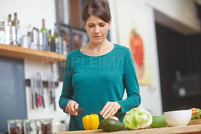 Buy stock photo Shot of an attractive woman chopping vegetables at a kitchen counter