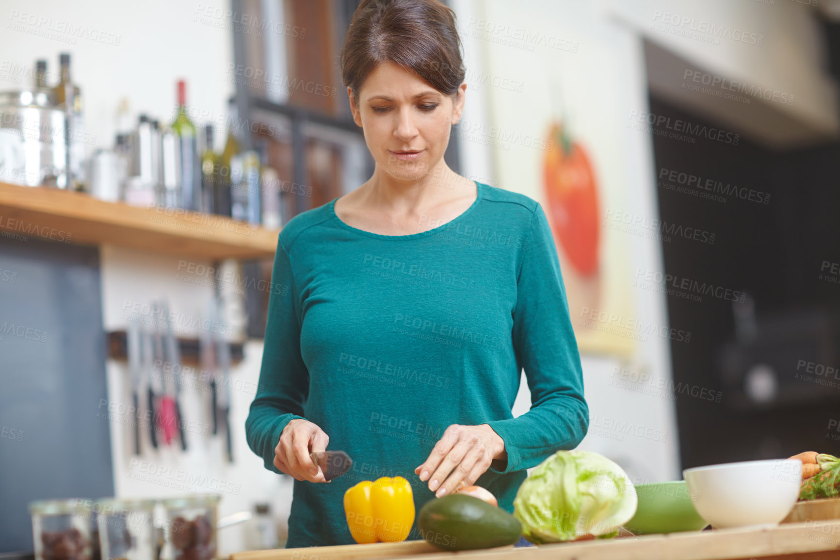 Buy stock photo Shot of an attractive woman chopping vegetables at a kitchen counter