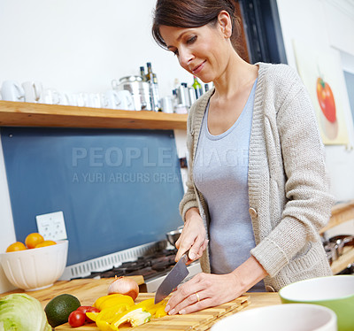 Buy stock photo Shot of an attractive woman chopping vegetables at a kitchen counter