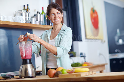 Buy stock photo Shot of an attractive woman making a fruit smoothie in the kitchen