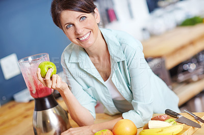 Buy stock photo Portrait of an attractive woman making a fruit smoothie in the kitchen