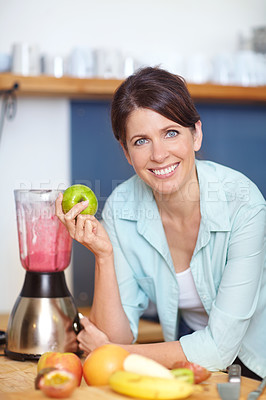 Buy stock photo Portrait of an attractive woman making a fruit smoothie in the kitchen