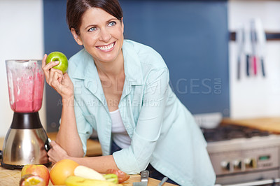 Buy stock photo Shot of an attractive woman making a fruit smoothie in the kitchen