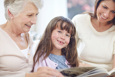 Buy stock photo Portrait, book and kid with mom and grandmother on sofa in living room for bonding together. Happy, relax and girl with mother and senior woman reading fantasy story, novel or literature at home.