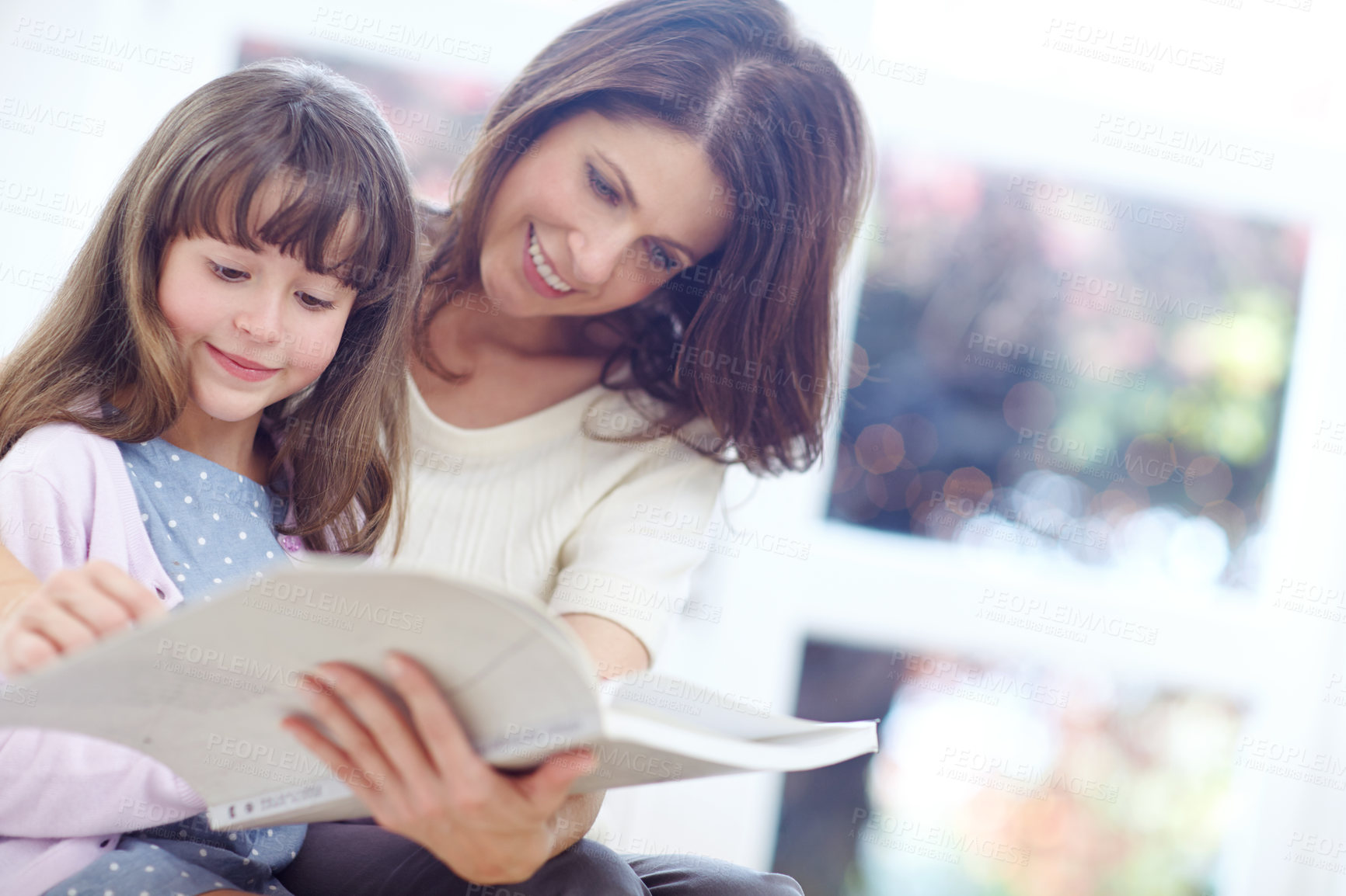 Buy stock photo Happy, book and kid reading with mother on sofa in living room for bonding together. Smile, relax and girl child enjoying fantasy novel, story or literature with mom on couch for learning at home.