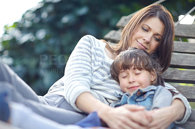 Buy stock photo Shot of a little girl napping in her mother's arms while lying on a hammock