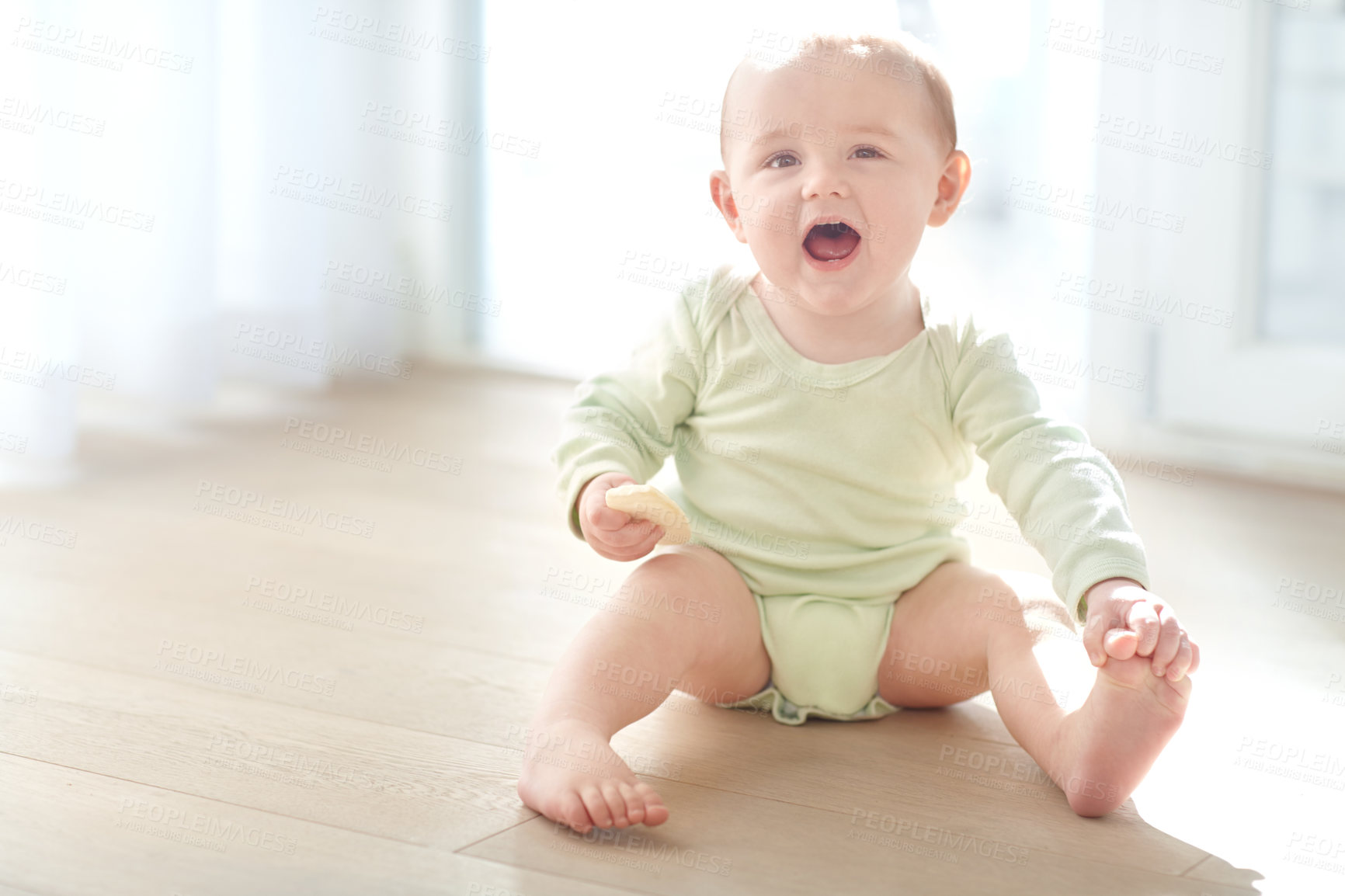 Buy stock photo Shot of a baby boy sitting on the floor while eating a snack