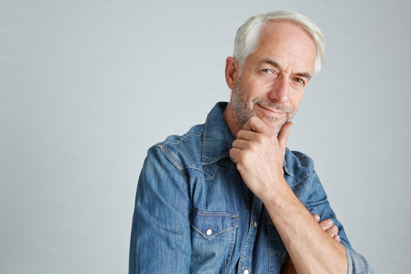 Buy stock photo Studio portrait of a handsome mature man standing with his hand on his chin