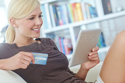 Buy stock photo Shot of a beautiful woman doing some online shopping at home using her digital tablet