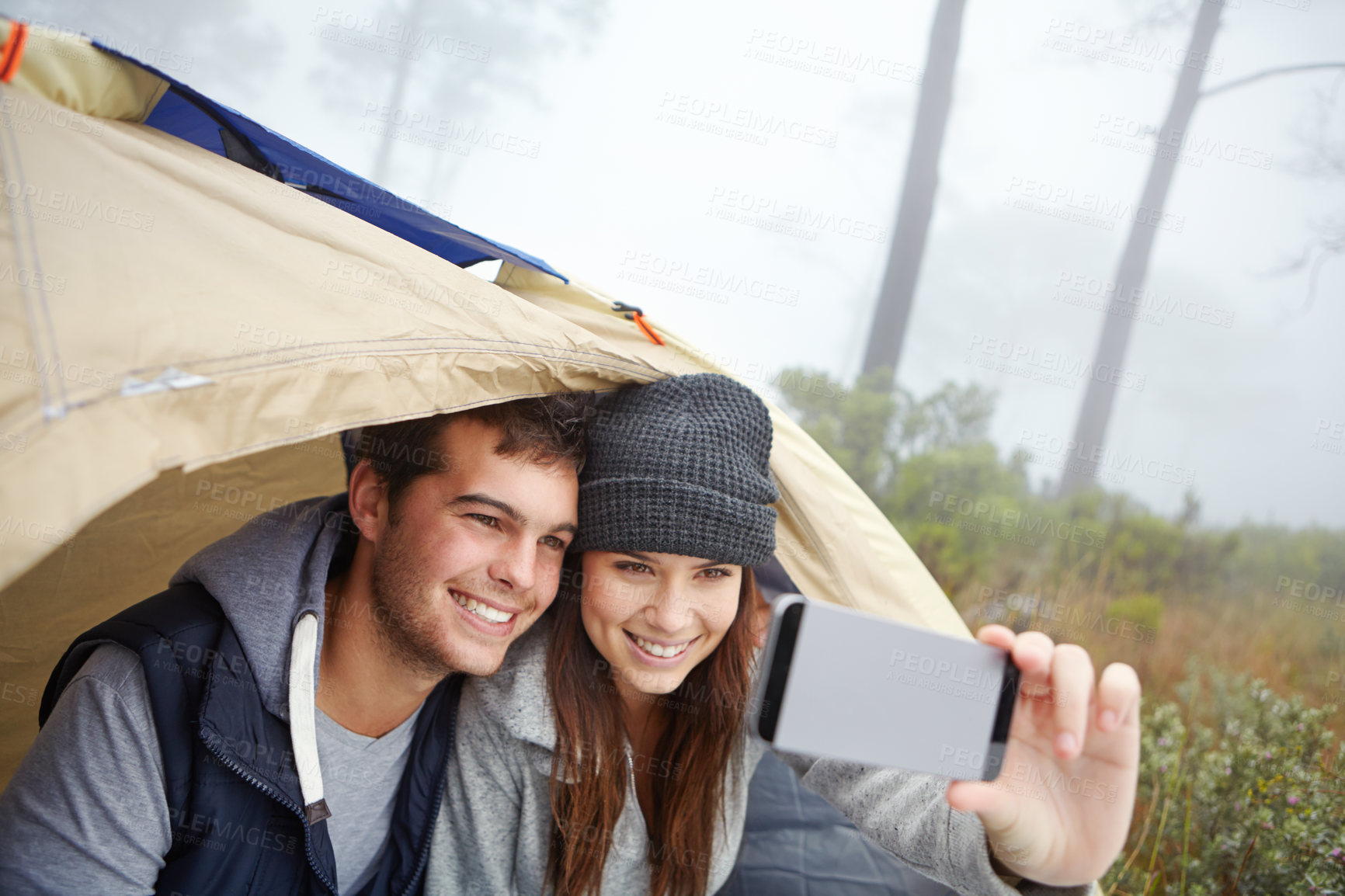 Buy stock photo Shot of a young couple taking a photo of themselves while on a camping trip