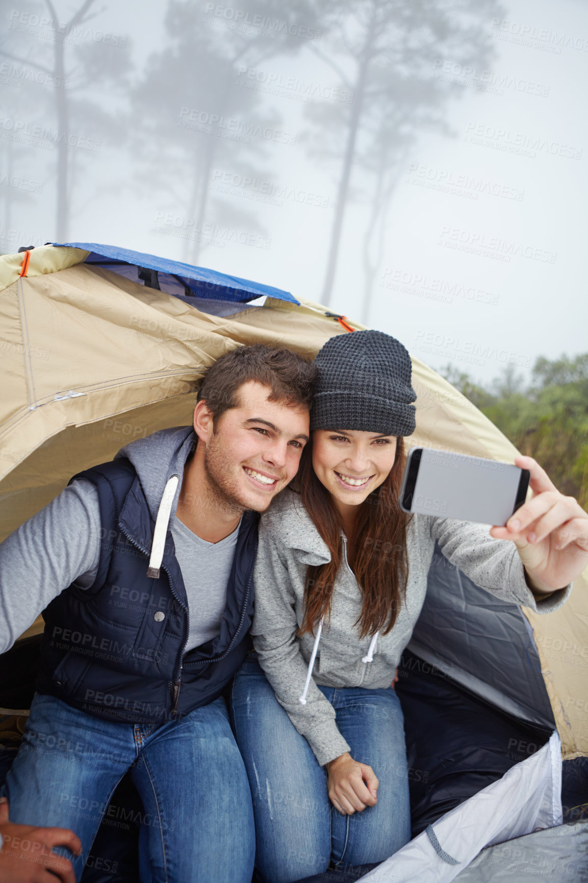 Buy stock photo Shot of a young couple taking a photo of themselves while sitting inside a tent