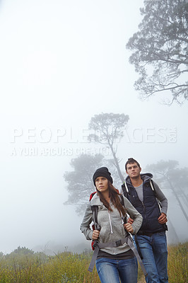 Buy stock photo Shot of a young couple hiking through nature