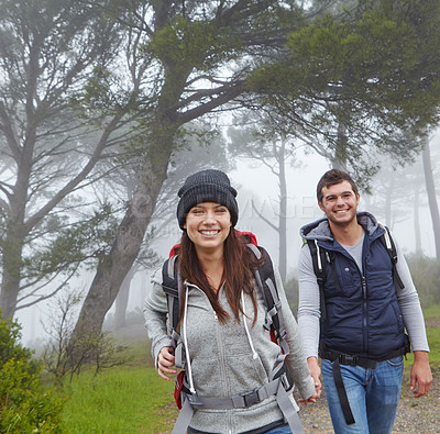 Buy stock photo Shot of a young couple hiking along a forest trail