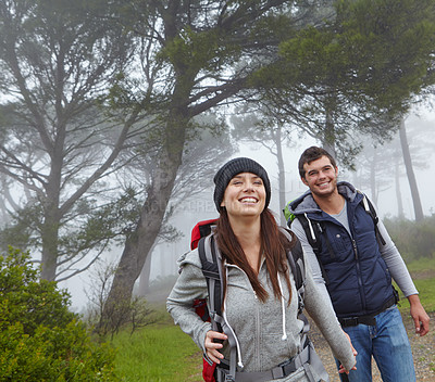 Buy stock photo Shot of a young couple hiking along a forest trail