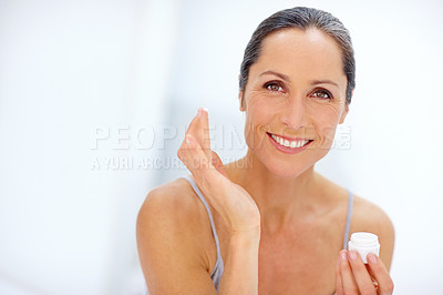 Buy stock photo Shot of an attractive mature woman applying moisturizer to her skin