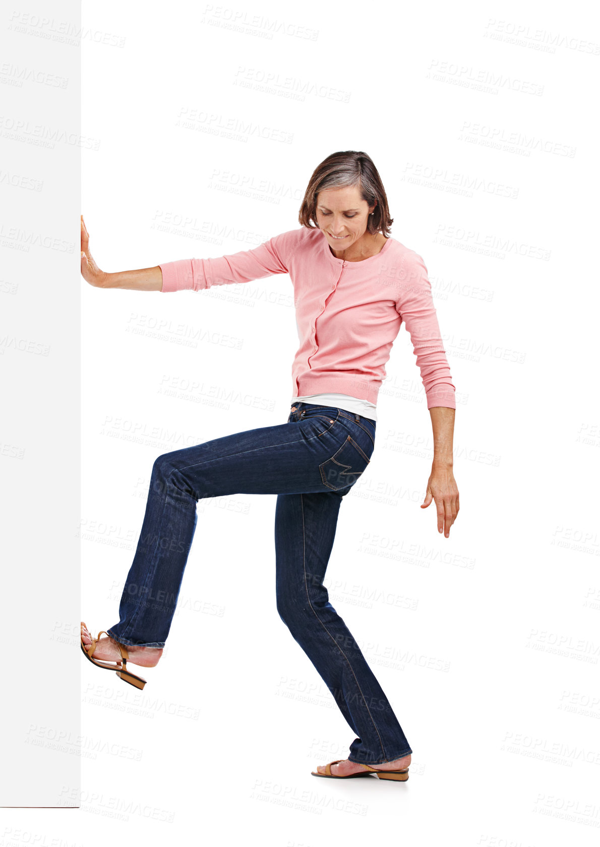 Buy stock photo Mature woman, wall and pushing with legs for rearrangments or change in studio on a white background. Female person, fashion and model moving heavy object, barricade or board in casual clothing