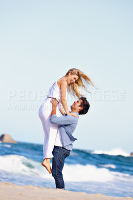 Buy stock photo Shot of a happy young couple enjoying a romantic day on the beach