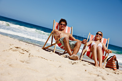 Buy stock photo Couple, sunglasses and relax at beach for travel, bonding and tropical holiday with chair on sand. Man, woman and ocean outdoor for trip, love and vacation with sunshine, smile and weekend in Greece