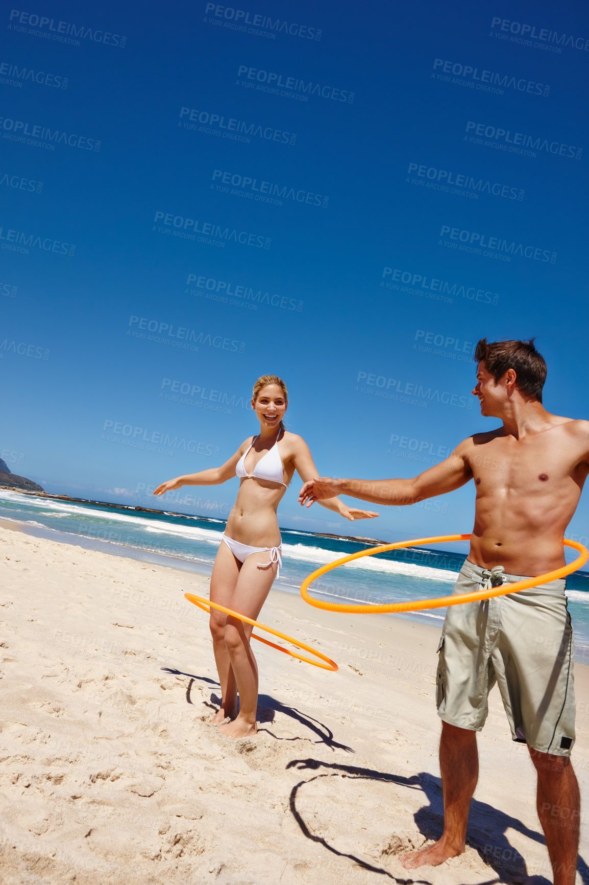 Buy stock photo Couple, plastic ring and beach play by waves together for fun, holiday or bonding with core exercise in nature. Happy people, game and Miami ocean with vacation, adventure and travel with trip