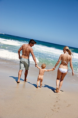 Buy stock photo Happy family, holding hands and beach with baby for summer holiday, weekend or bonding in nature. Mother, father and toddler or kid walking with parents on ocean coast for fun outdoor vacation by sea