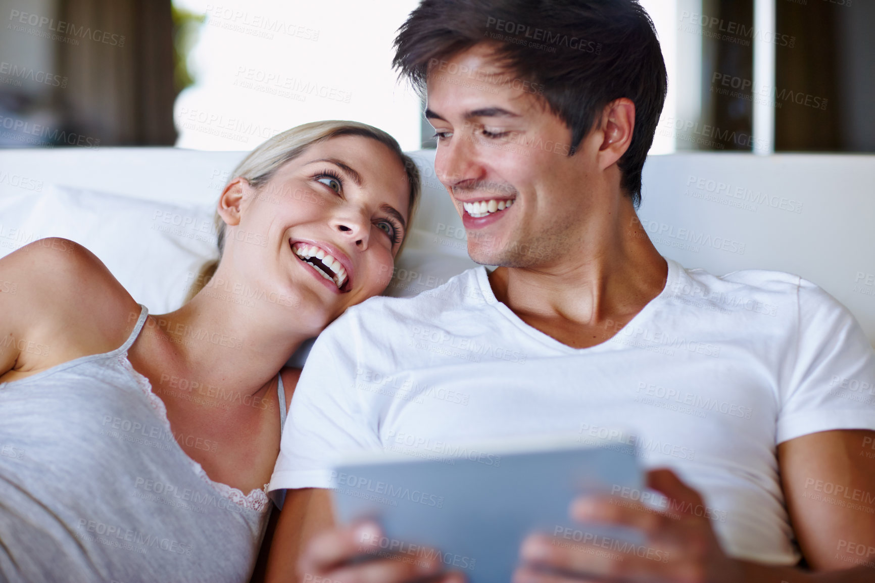 Buy stock photo Couple, smile and tablet on bed for relax, bonding and streaming movie with website, app and video. Man, woman and technology in home for relationship, love and social media with film subscription