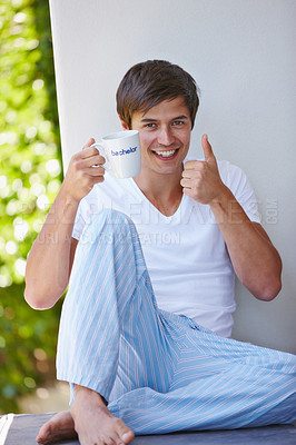 Buy stock photo Portrait, happy man and thumbs up with coffee in home, balcony or relax on bachelor pad. Smile, tea and like hand gesture for online dating promotion, opportunity and single person with words on cup