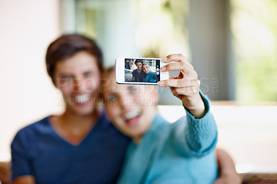 Buy stock photo Shot of a happy young couple taking a selfie together on a mobile phone