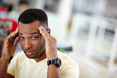 Buy stock photo Shot of a handsome young man suffering from a headache at work