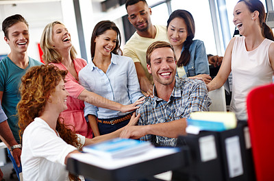 Buy stock photo Shot of a young man being congratulated by his colleagues at the office