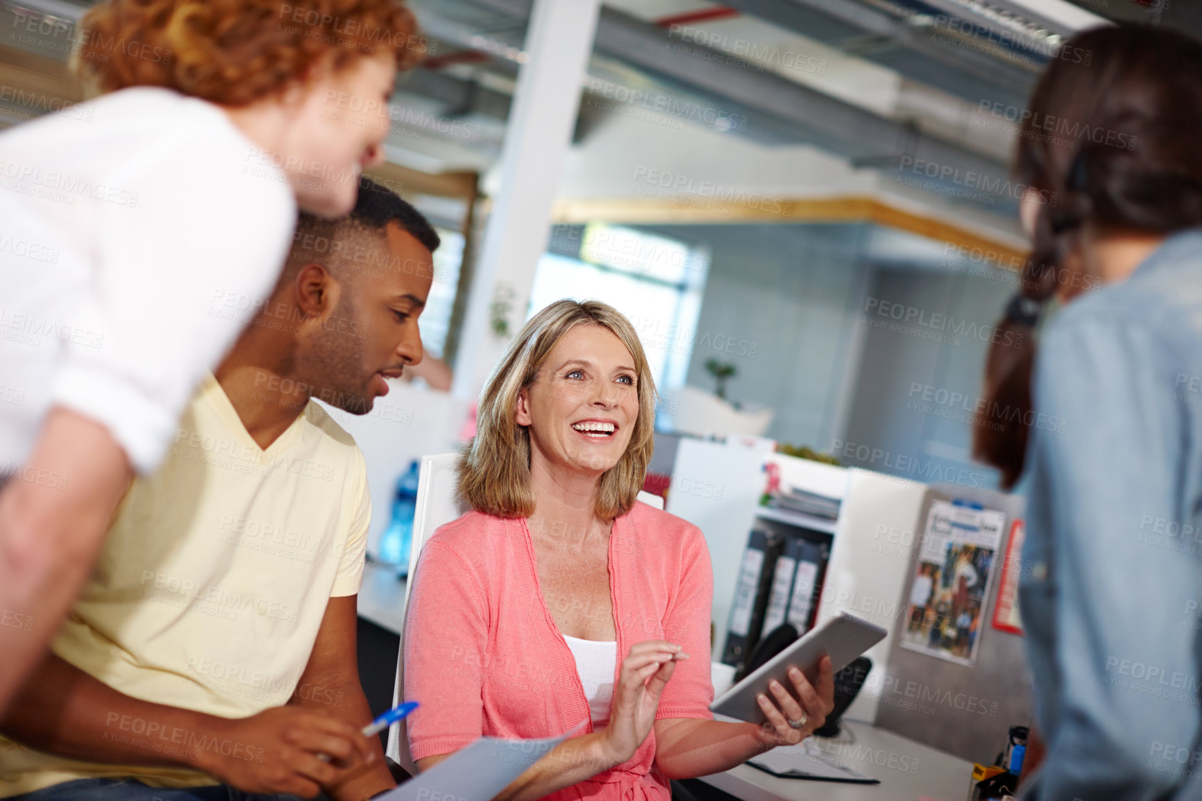 Buy stock photo Shot of a a beautiful woman showing her coworkers something on a tablet in a casual work environment