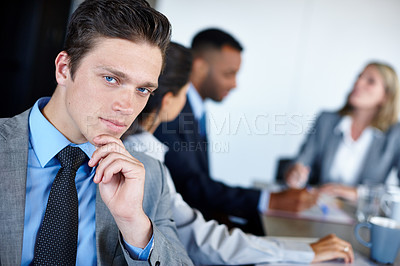 Buy stock photo Portrait of a young businessman sitting in the boardroom with his colleagues during a meeting