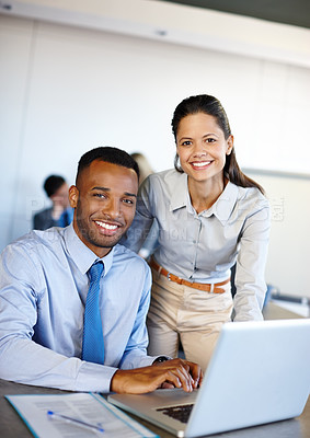 Buy stock photo Shot of two young coworkers working together on a laptop in the office