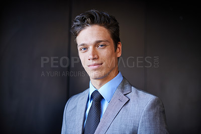 Buy stock photo Portrait of one handsome confident young caucasian businessman in a suit and tie standing against a dark background. Ambitious entrepreneur and dedicated corporate leader ready for success 