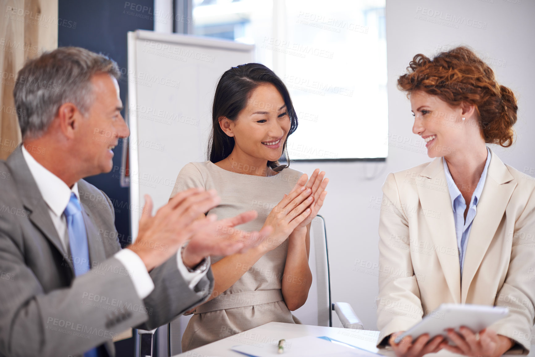 Buy stock photo Shot of two businesspeople congratulating their colleague in a meeting
