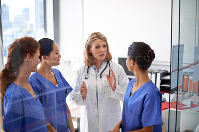 Buy stock photo Shot of a female doctor assigning tasks to a group of nurses at a hospital