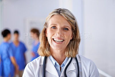 Buy stock photo Portrait of a mature female doctor with a group of nurses standing in the background