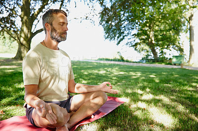 Buy stock photo Shot of a handsome mature man meditating in the lotus position outdoors