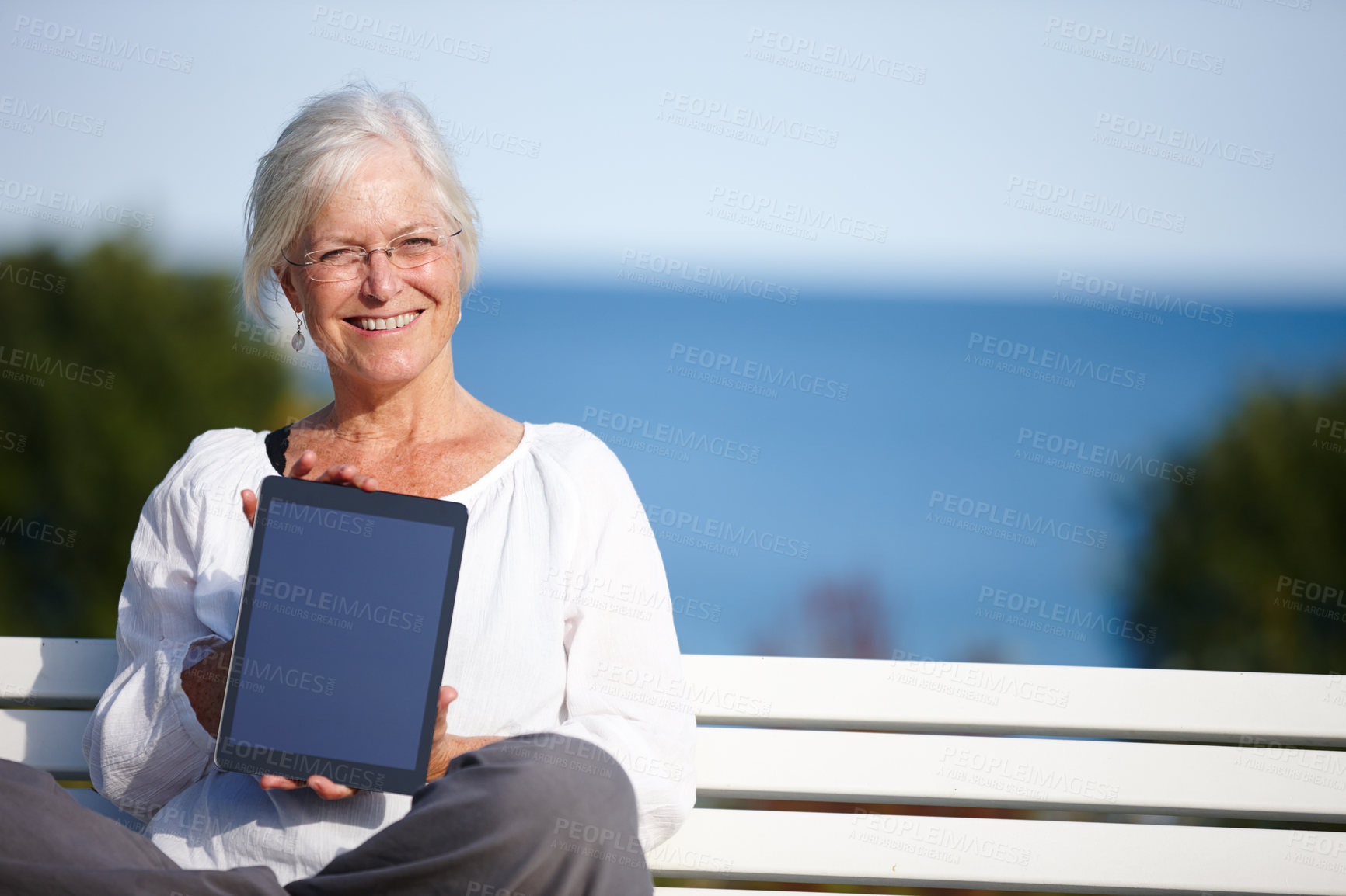 Buy stock photo Happy woman, portrait or bench with tablet screen for advertising, marketing or outdoor app. Mature, female person or smile with technology display for tutorial, health tips or mockup space at beach