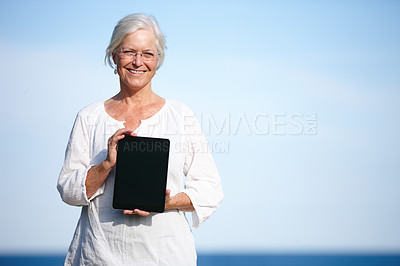 Buy stock photo Portrait of a mature woman holding up a digital tablet while standing outside