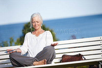 Buy stock photo Shot of a mature woman listening to music while doing a relaxation exercise outdoors