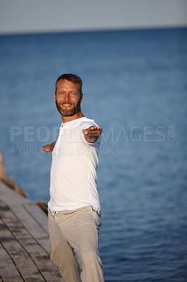 Buy stock photo Coast, man and stretching on portrait for fitness, yoga and exercise in German. Male person, outdoor and smile or satisfied for retirement on break with self care, wellness or health with arms open