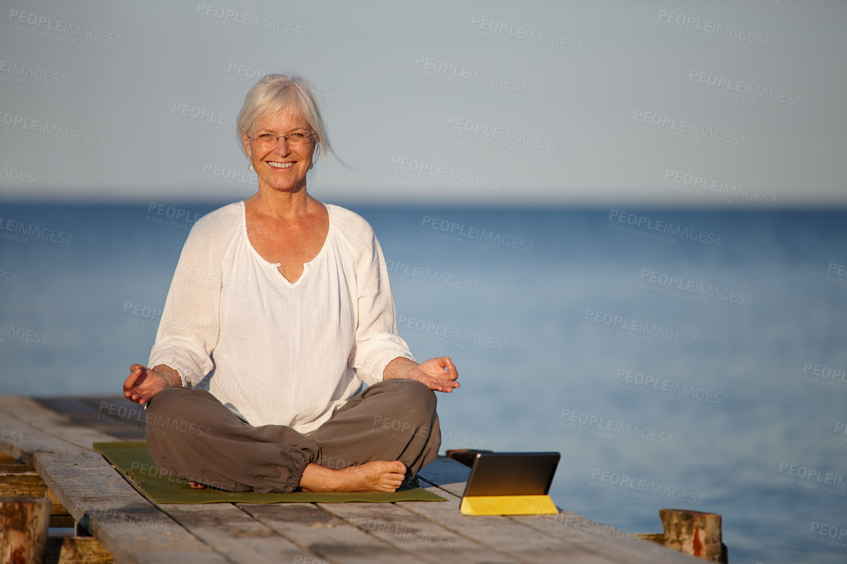 Buy stock photo Mature woman, portrait and meditation with tablet by lake for online tutorial, lesson or virtual class in nature. Happy senior, female person or yogi with smile for holistic, inner peace or exercise