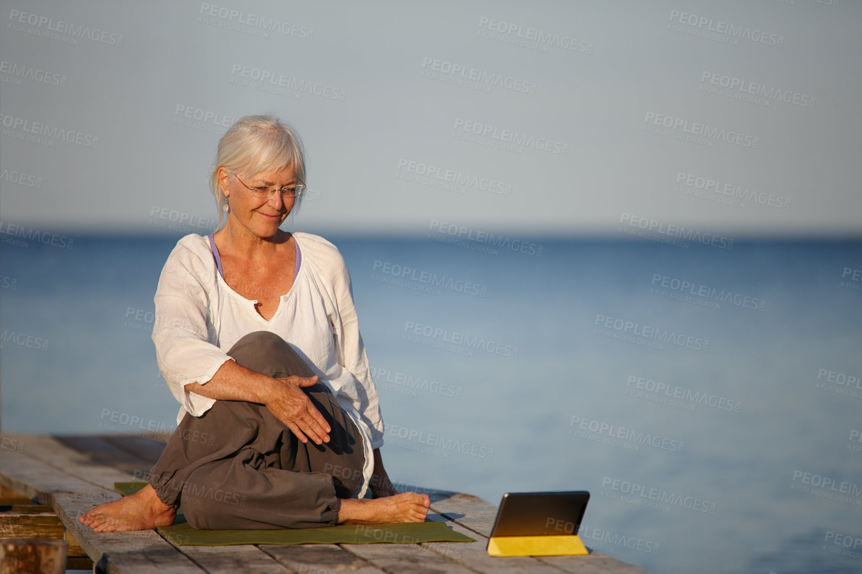 Buy stock photo Mature woman, yoga and lake with tablet for online tutorial, lesson or virtual class in nature. Senior, female person or yogi with smile for holistic training, workout or exercise by beach or ocean