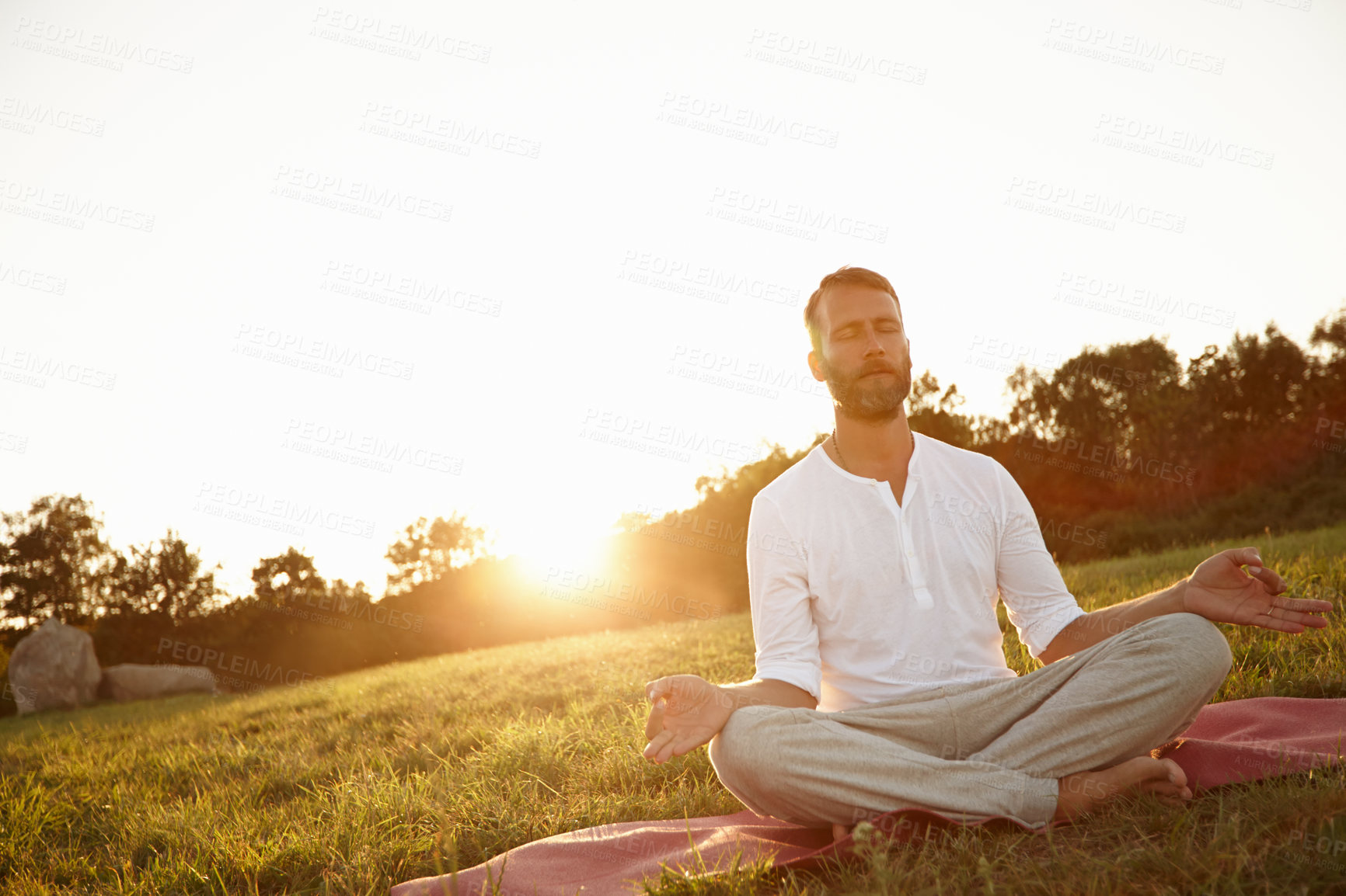 Buy stock photo Shot of a handsome mature man meditating in the outdoors at sunset